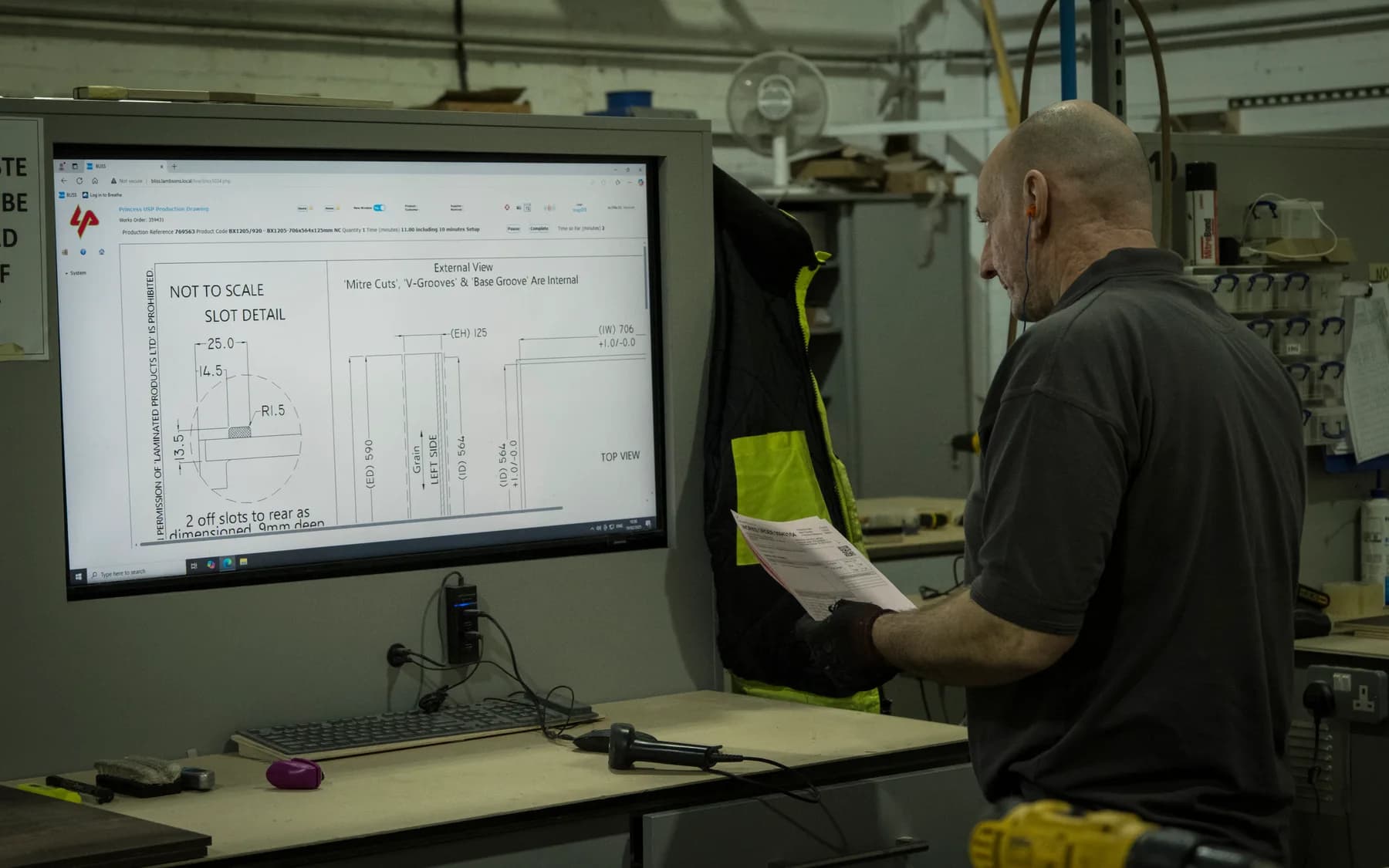 An operator reading a technical drawing at the workstation