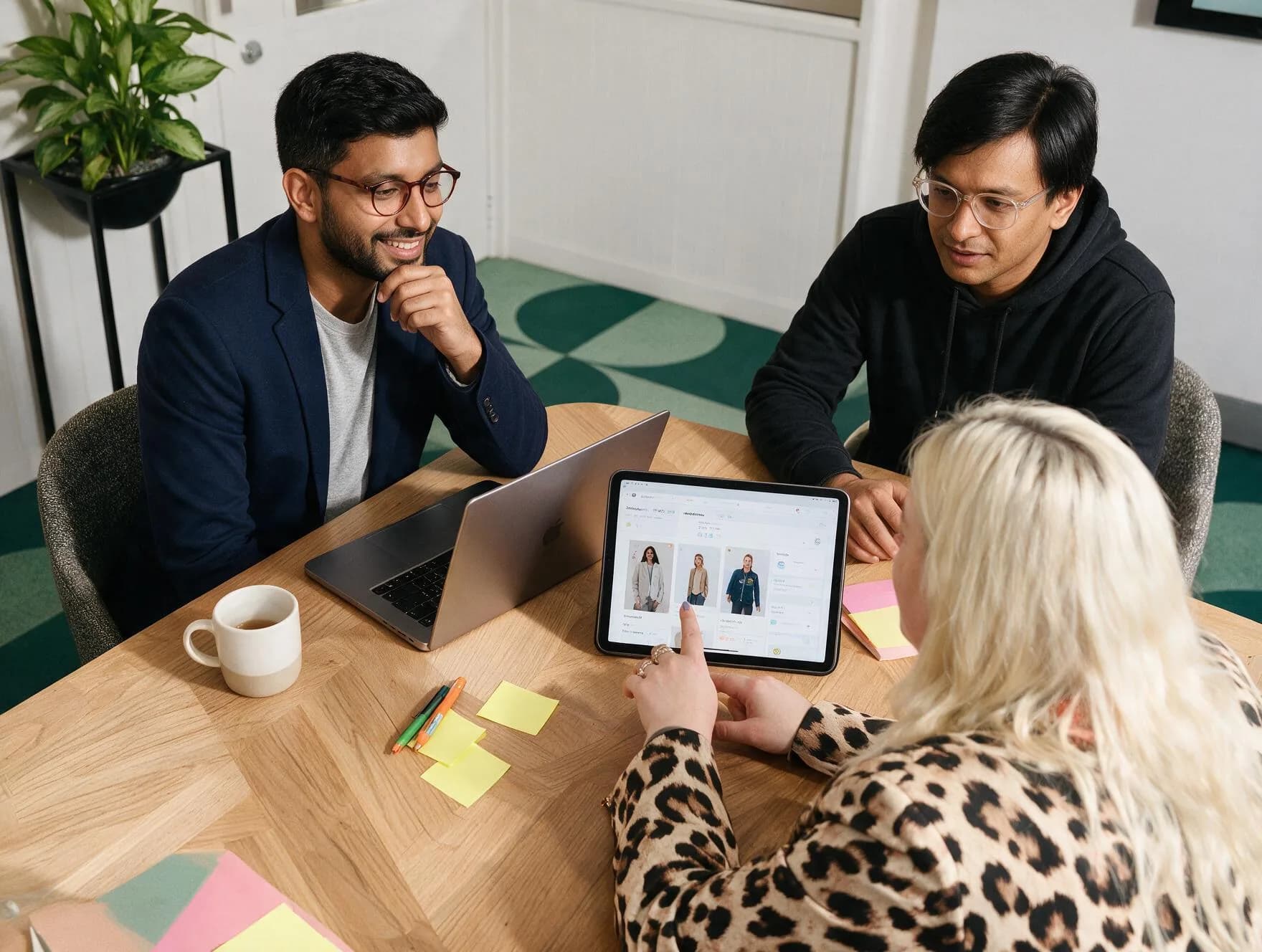 Three people around a table in the Unovo studio, looking at a site design on a tablet