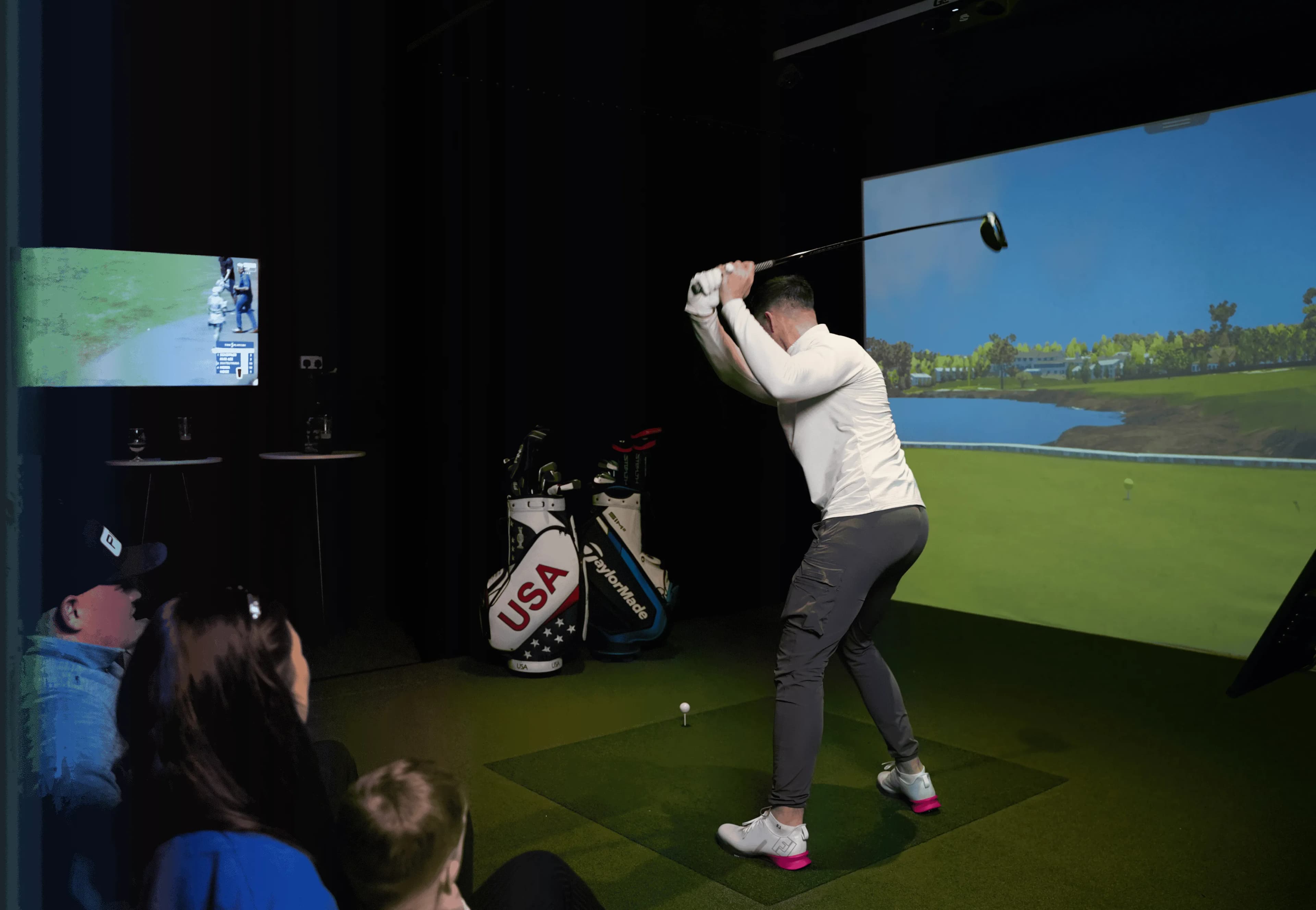 A player mid-swing in a simulator bay