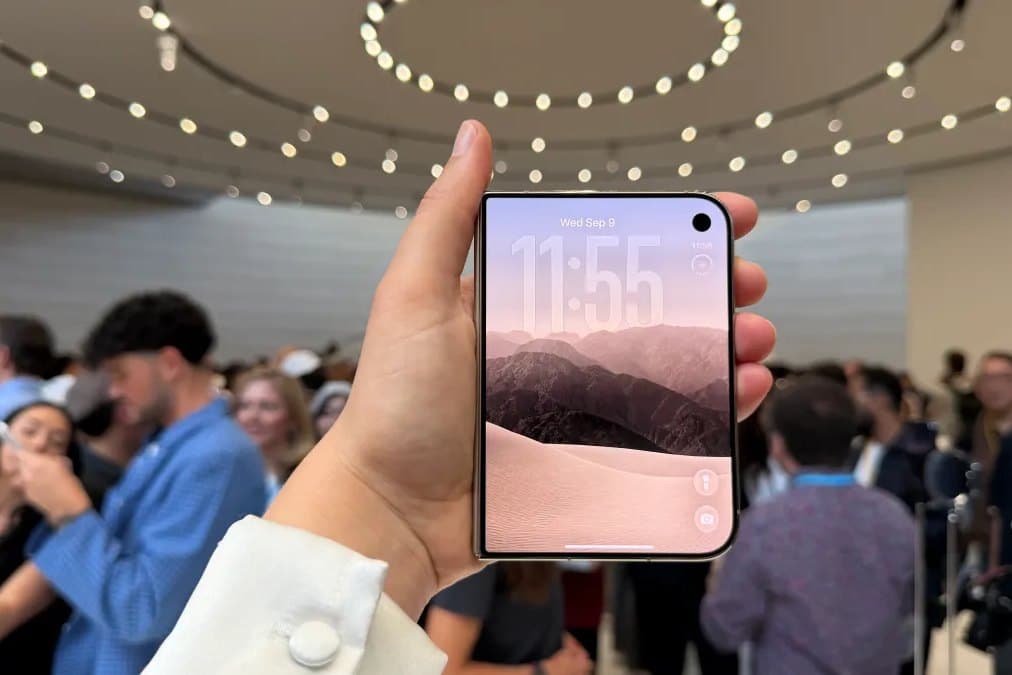 A foldable iPhone Duo held open above a seated audience at Apple Park.