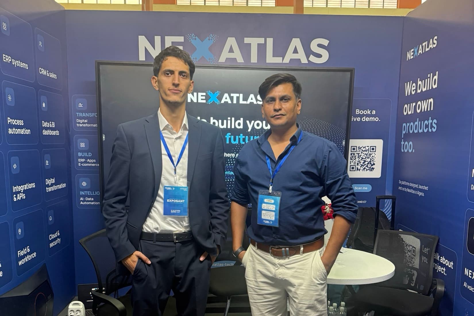 Usman, in a navy shirt and white trousers, standing beside a colleague in a dark suit on the NexAtlas exhibition stand.